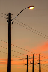 Electrifying posts with orange sunset sky background.