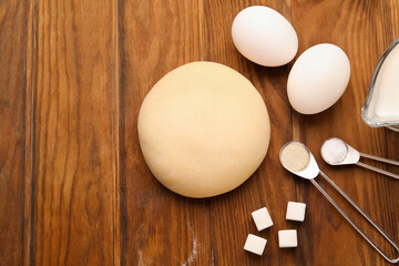 Fresh dough and ingredients on wooden background, closeup