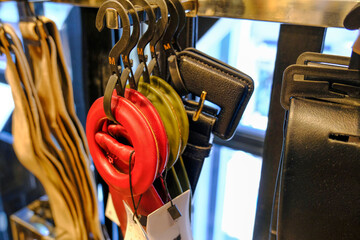 Multicolored leather belts on hangers close-up in the fashion store. Personal accessories. Stylish outfit