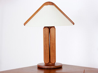 A vintage modern desk lamp from the 60s made out of tak wood standing on a desk isolated on white...