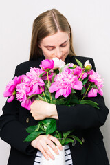 Young woman hugs a bouquet of flowers