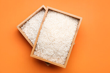 Wooden boxes with raw rice on color background
