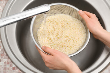 Woman rinsing rice in sifter under running water