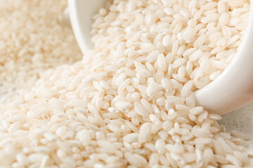 Overturned bowl with raw rice on table, closeup