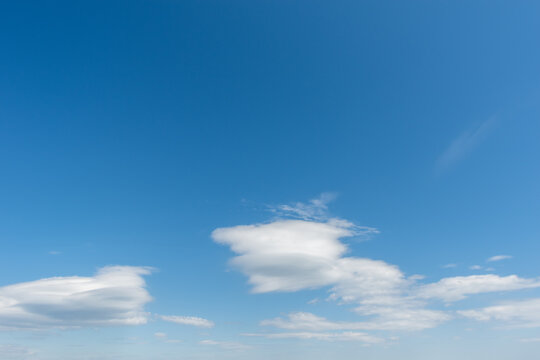 Blue sky with light fluffy swirling white clouds. Perfect natural sky background for your photos