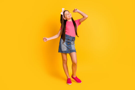 Photo of confident funny school girl wear pink t-shirt smiling dancing isolated yellow color background