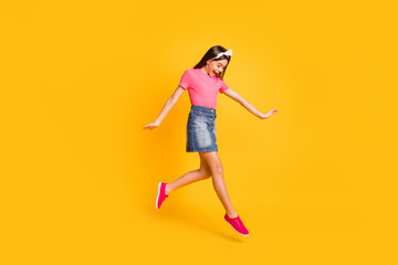 Photo of sweet impressed school girl wear pink t-shirt smiling jumping high looking footwear isolated yellow color background