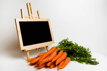 A bunch of carrots and a blackboard on a white background