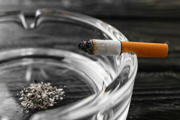 Ash tray and cigarette on dark wooden background, closeup