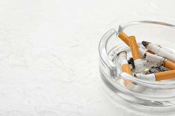 Ash tray with cigarettes on light background