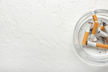 Ash tray with cigarettes on light background