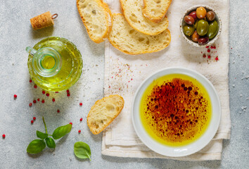 Freshly baked homemade ciabatta and a sauce of olive oil and balsamic vinegar, freshly ground pink pepper, coarse sea salt and basil  on a light background. Mediterranean cuisine
