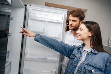 Fototapeta na wymiar Young couple selecting new refrigerator in household appliance store