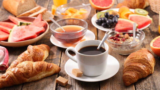 breakfast with coffee cup, tea cup, fruit and croissant