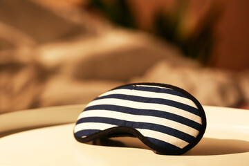 Stylish sleeping mask on table in bedroom