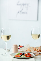 Plates with fresh Greek salad and glasses of wine on table in restaurant
