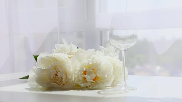 peonies flowers on the table pouring wine glass