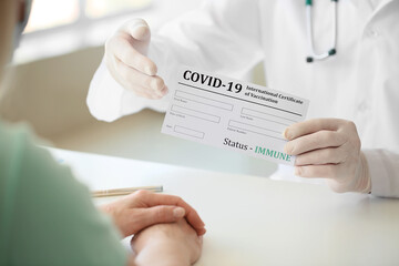 Doctor giving patient her International Certificate of Vaccination in clinic, closeup