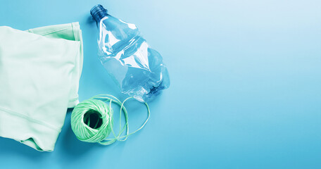 The concept recycling plastic. Empty plastic bottle and recycled polyester fiber, synthetic fabric blue background