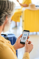 Senior tourist with electronic immune passport at the airport