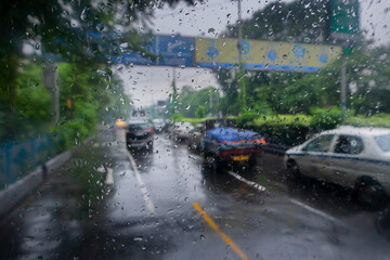 Image shot through raindrops falling on wet glass, abstract blurs of traffic - monsoon stock image of Kolkata (formerly Calcutta) city ,