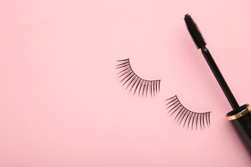 Black eyelashes and mascara on pink background with copy space.