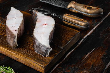 Raw steak of white fish, with ingredients and rosemary herbs, on old dark  wooden table background,...