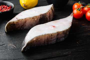 Raw fresh halibut fish steak, with ingredients and rosemary herbs, on black wooden table background