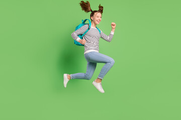 Fototapeta na wymiar Photo of hurrying cute small schoolgirl dressed striped sweater rucksack running jumping empty space isolated green color background