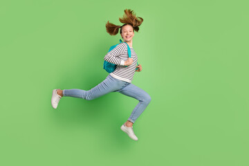 Fototapeta na wymiar Photo of cute charming small schoolgirl dressed striped sweater rucksack running jumping high isolated green color background