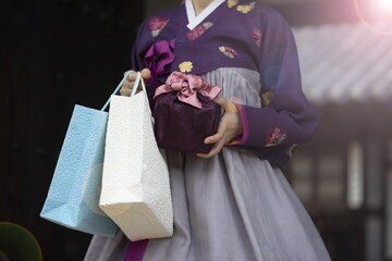Woman in Korean traditional clothes holding traditional package and shopping bags