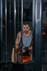 Fototapeta na wymiar Fit mature man resting in between exercises in a gym