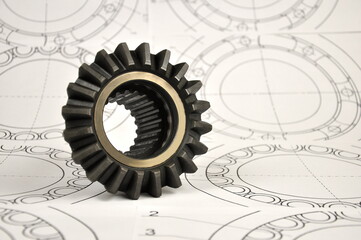 Metal cogwheel on the background of drawings. Spare parts.