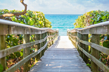 Wooden pier leading out to beautiful beach. - obrazy, fototapety, plakaty