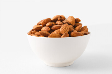 Almond nuts in a white bowl on isolate white background with clipping path, selective focus.front view.