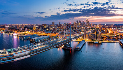Aerial panorama with Ben Franklin Bridge and Philadelphia skyline in transition from sunset to dusk. Ben Franklin Bridge is a suspension bridge connecting Philadelphia and Camden, NJ. - Powered by Adobe