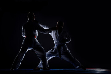 Karate kata training men isolated on dark background