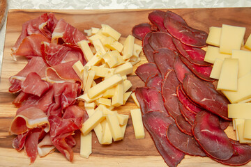 Cold sliced ​​assorted meat and cheese on a wooden board close-up. Photo of food
