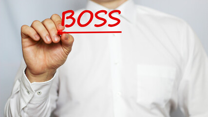 A businessman in a white shirt writes a text BOSS on a white background with a red marker . business concept