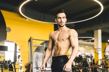 Fototapeta na wymiar Handsome young sporty male bodybuilder with naked torso posing in the gym