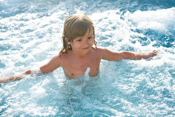 Happy kid playing in outdoor swimming pool on hot summer day. Kids learn to swim. Child in water. Children play in tropical resort. Family beach vacation.