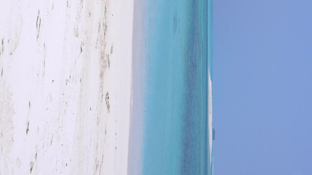 Santa Claus on tropical beach with white sand and azure sea water. Christmas holidays on islands. Vertical format video