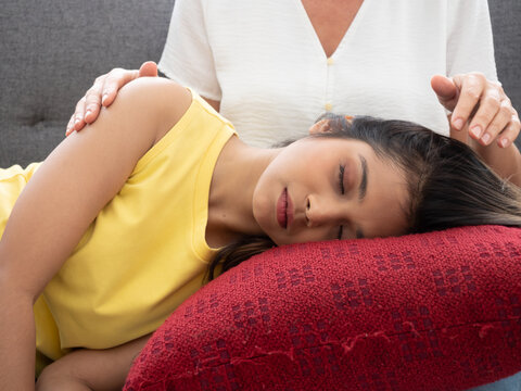 The adopted caucasian mother care of her Asian teen daughter while she is sleeping on his lap. love and sharing time of stepmother, stepdaughter concept.