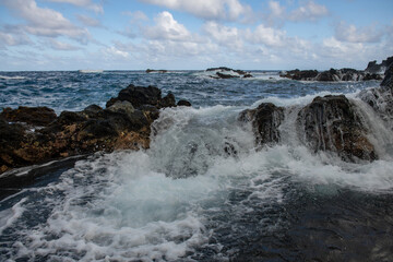 Fototapeta na wymiar Splashing waves on the rock in the sea. Wave hit the stone in the ocean with a water background.