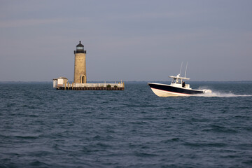 boat cruising past a lighthouse.