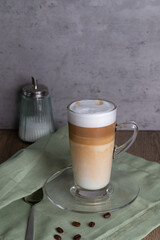 A glass mug with coffee latte macchiato on the table in the background a sugar bowl, copy space