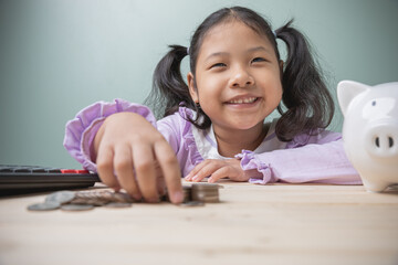 Naklejka premium Cute Asian kid girl smile happiness is counting money for saving money to the future. Concept to save money for education. Ideas savings money for tuition fees, the cost of school supplies.