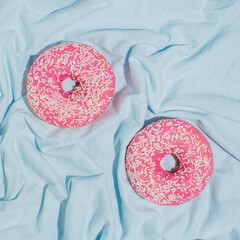 Minimalistic summer vibes concept with pink donuts on bright blue fabric. Creative water and summer...