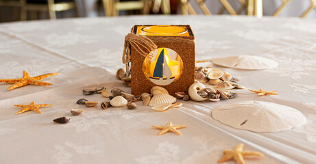 Table decorated with a by the sea theme shells and sailboat candle holder