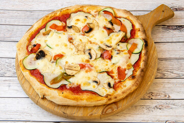 Spectacular vegetarian pizza recipe with thin crust, mushrooms, peppers and zucchini on unvarnished wooden board